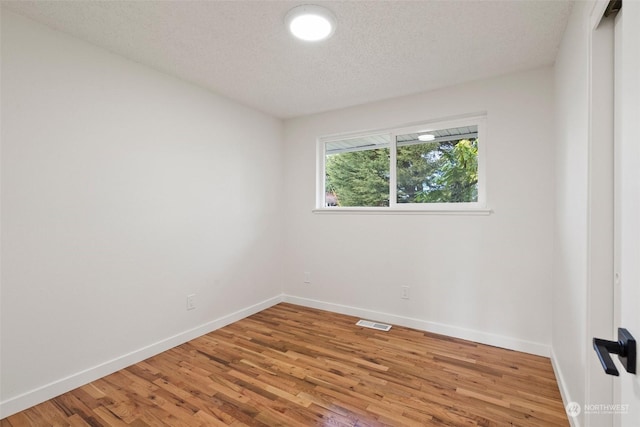 empty room with hardwood / wood-style floors and a textured ceiling