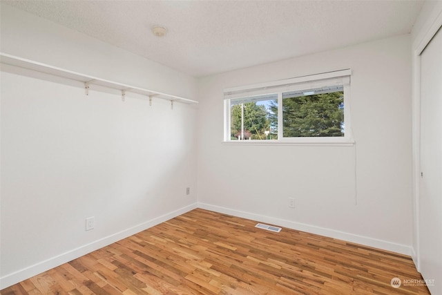 spare room featuring hardwood / wood-style flooring and a textured ceiling