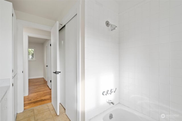 bathroom with tiled shower / bath combo and tile patterned flooring