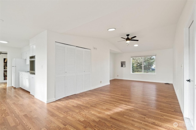 unfurnished bedroom with white fridge, lofted ceiling, ceiling fan, and light hardwood / wood-style flooring