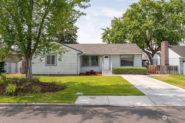 ranch-style home with roof with shingles, a front yard, and fence