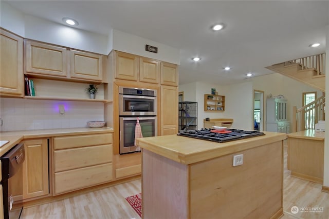 kitchen featuring stainless steel appliances, a kitchen island, light brown cabinets, and light hardwood / wood-style floors