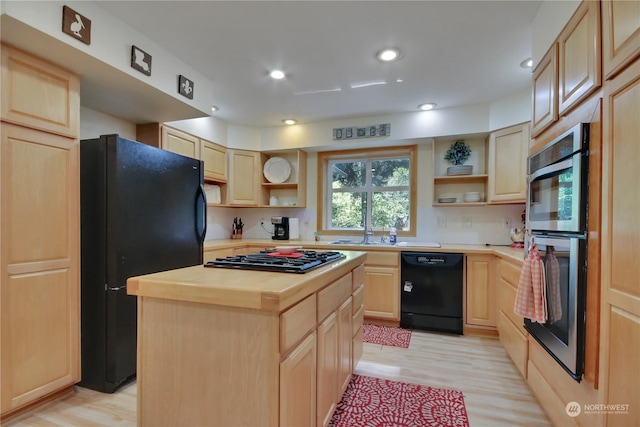 kitchen featuring a kitchen island, butcher block countertops, black appliances, light brown cabinets, and light hardwood / wood-style flooring