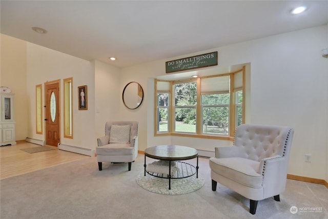 living area with a baseboard heating unit and light colored carpet