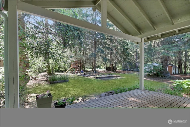 view of yard featuring a playground, a wooden deck, and a trampoline