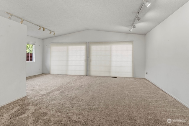 empty room featuring carpet flooring, rail lighting, a textured ceiling, and vaulted ceiling