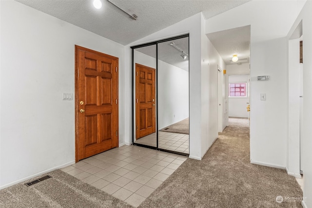 carpeted entryway featuring a textured ceiling and vaulted ceiling