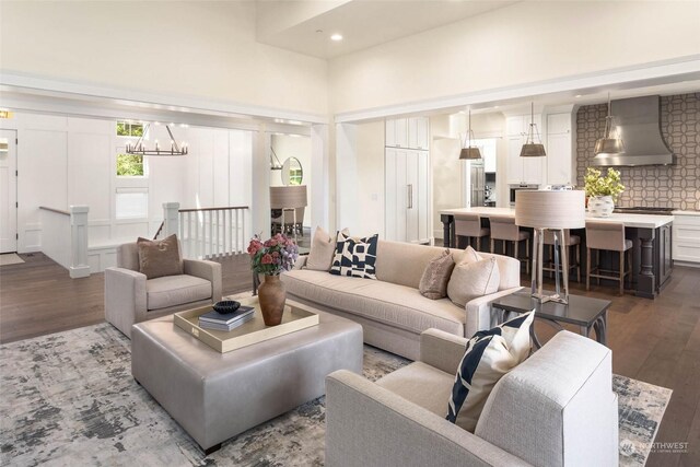 living room featuring hardwood / wood-style floors, a towering ceiling, and a chandelier