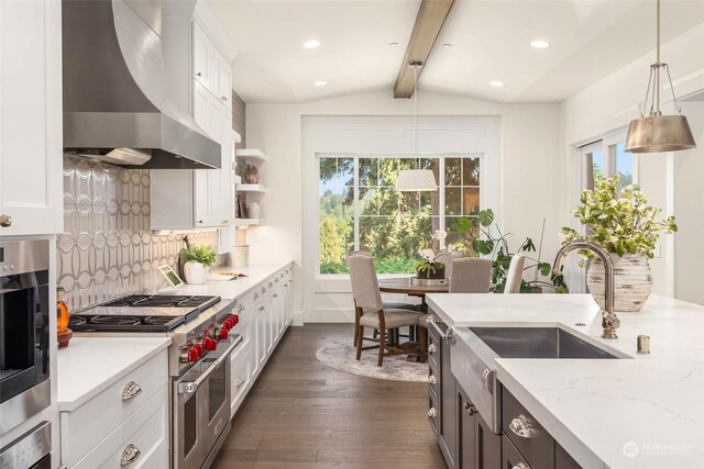 kitchen with double oven range, white cabinets, pendant lighting, and wall chimney range hood