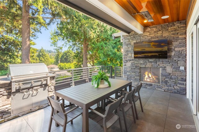 view of patio with an outdoor stone fireplace and area for grilling