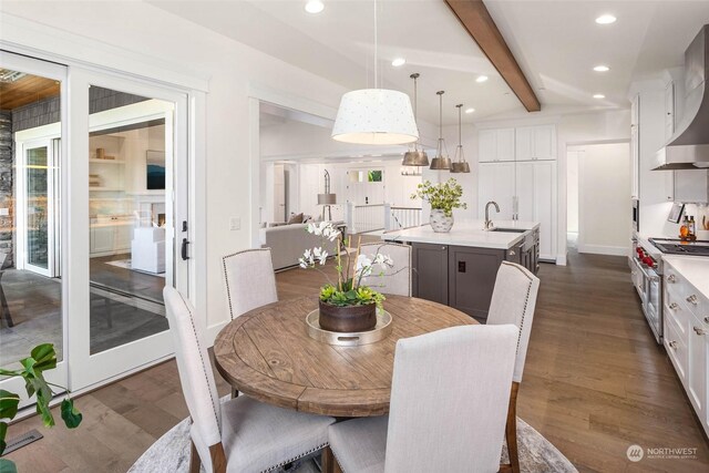 dining area with beam ceiling, dark hardwood / wood-style floors, and sink