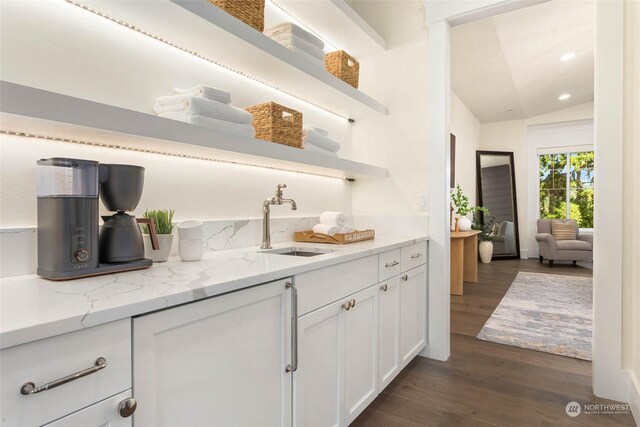 bar featuring white cabinetry, sink, light stone countertops, dark wood-type flooring, and vaulted ceiling