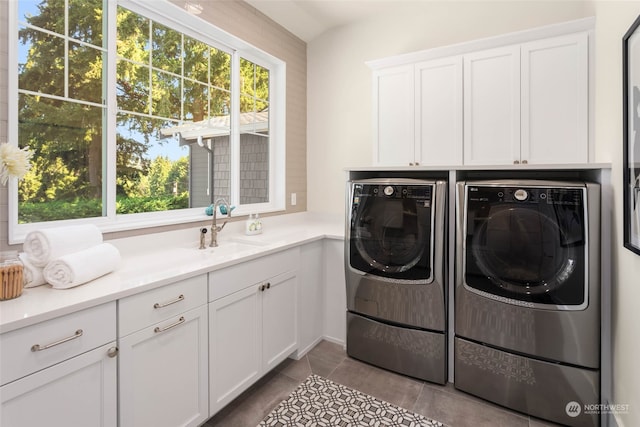 laundry area with cabinets, light tile patterned floors, sink, and washing machine and clothes dryer