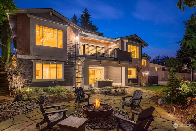 rear view of property featuring a patio, a balcony, and an outdoor fire pit