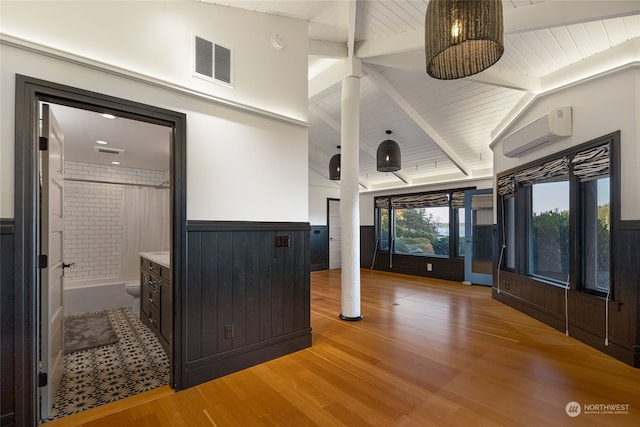 interior space featuring lofted ceiling with beams, vanity, toilet, a wall mounted AC, and walk in shower