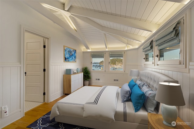 bedroom featuring light wood-type flooring and vaulted ceiling with beams