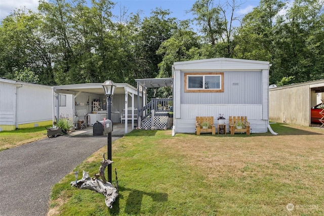 manufactured / mobile home featuring a carport, aphalt driveway, and a front yard