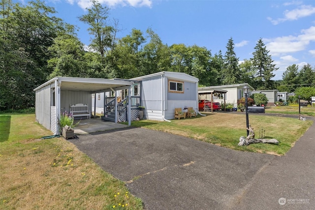 manufactured / mobile home with aphalt driveway, a front lawn, and a detached carport