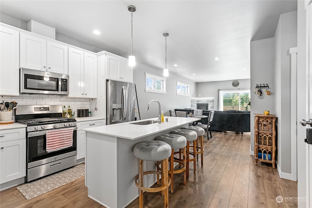 kitchen with tasteful backsplash, stainless steel appliances, light hardwood / wood-style floors, and white cabinets