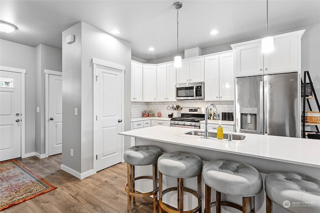 kitchen featuring hanging light fixtures, appliances with stainless steel finishes, tasteful backsplash, and light wood-type flooring