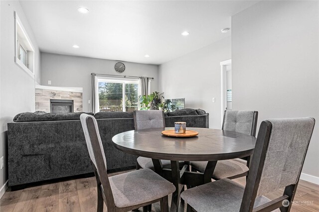 dining space with a tile fireplace and wood-type flooring