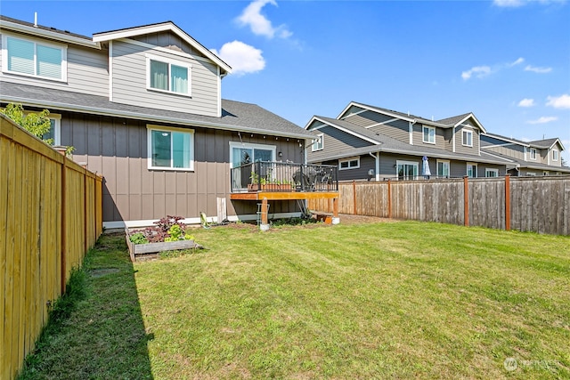 back of property with a yard and a wooden deck