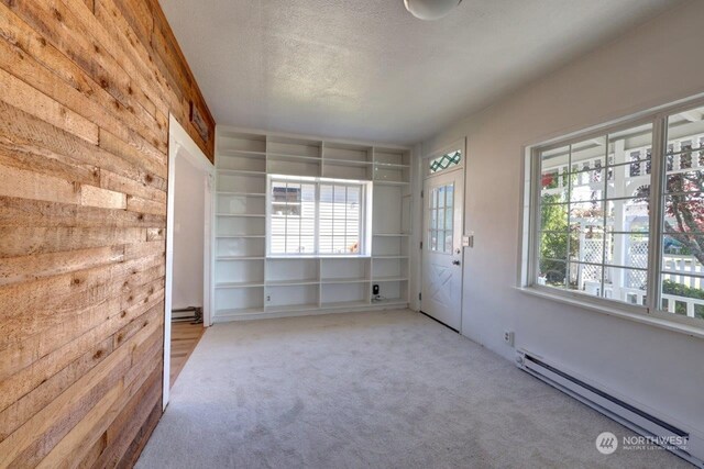 unfurnished bedroom featuring multiple windows, light colored carpet, a baseboard radiator, and a textured ceiling