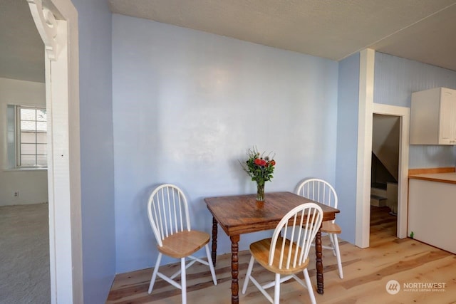 dining space with a textured ceiling and light hardwood / wood-style floors