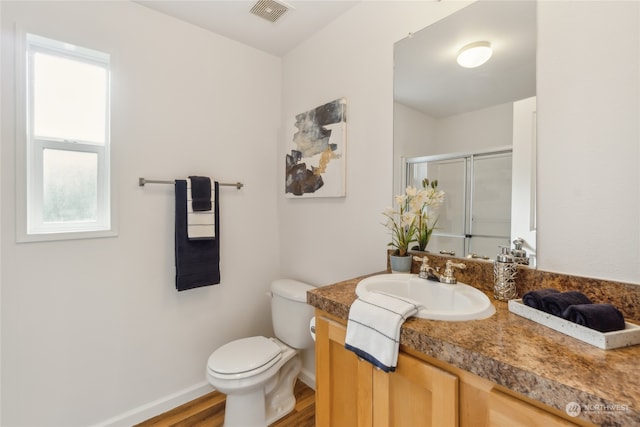 bathroom featuring toilet, visible vents, vanity, baseboards, and a stall shower