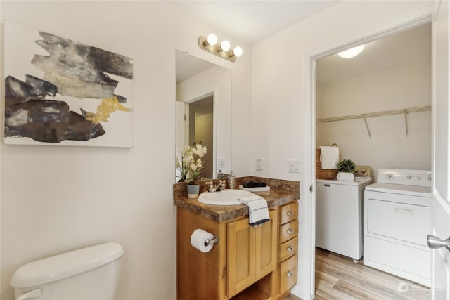 bathroom featuring independent washer and dryer, vanity, toilet, and wood finished floors