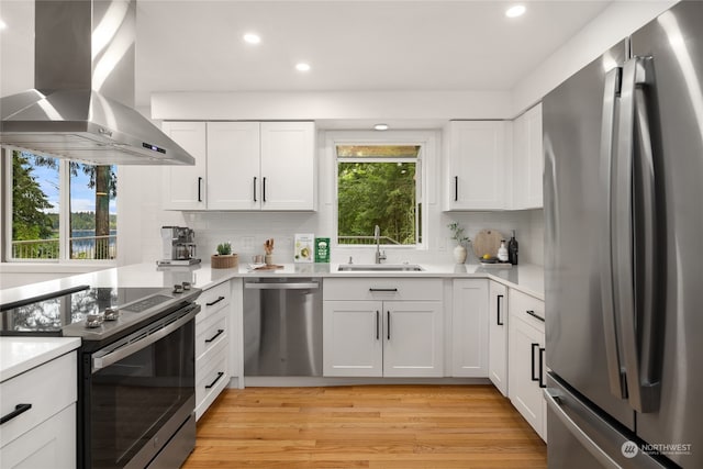 kitchen with light wood-type flooring, appliances with stainless steel finishes, white cabinets, and island range hood