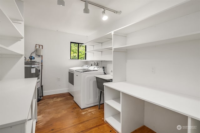 laundry area with rail lighting, washer and clothes dryer, electric water heater, and hardwood / wood-style flooring