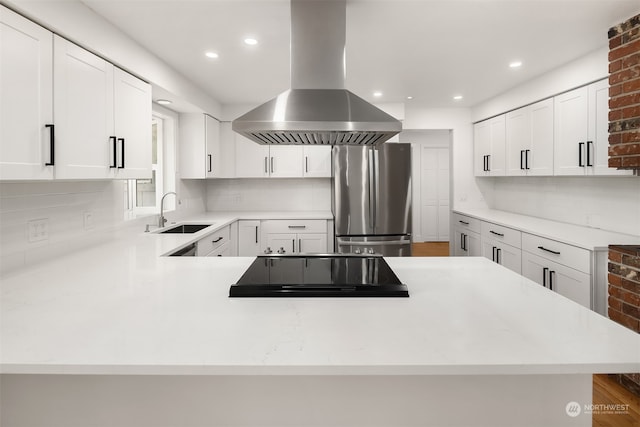 kitchen with hardwood / wood-style floors, stainless steel fridge, backsplash, sink, and island exhaust hood