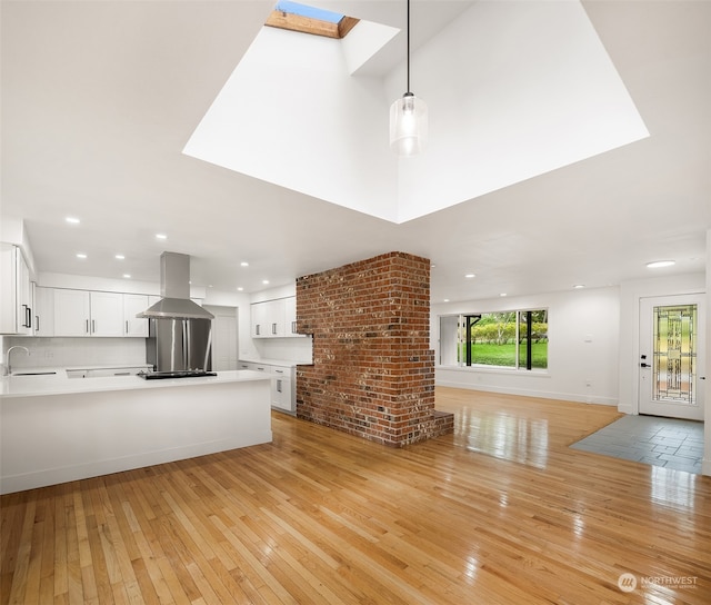 unfurnished living room with brick wall, a skylight, light hardwood / wood-style floors, and sink