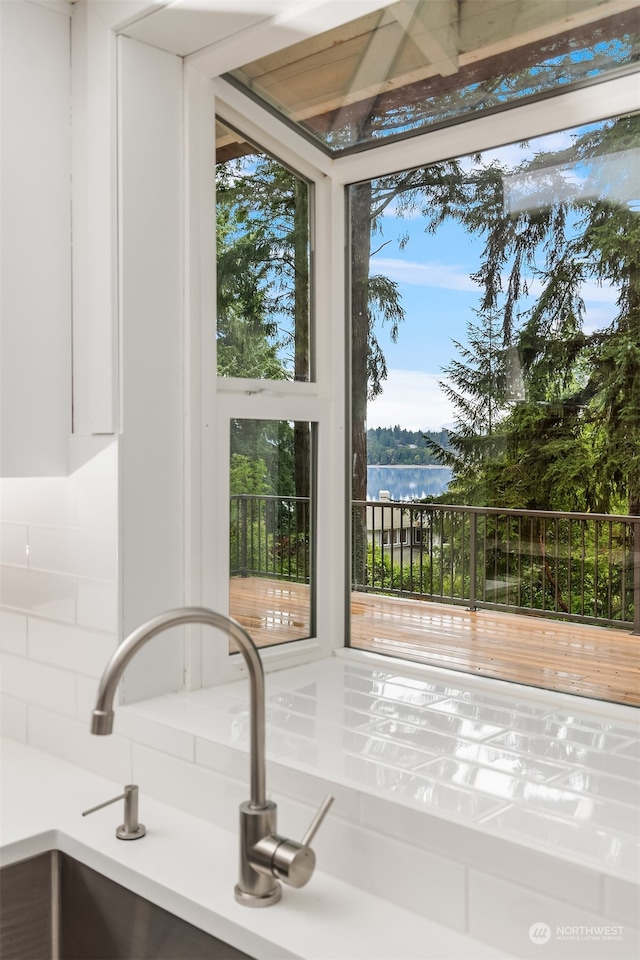 interior details featuring a water view, white cabinets, and tasteful backsplash