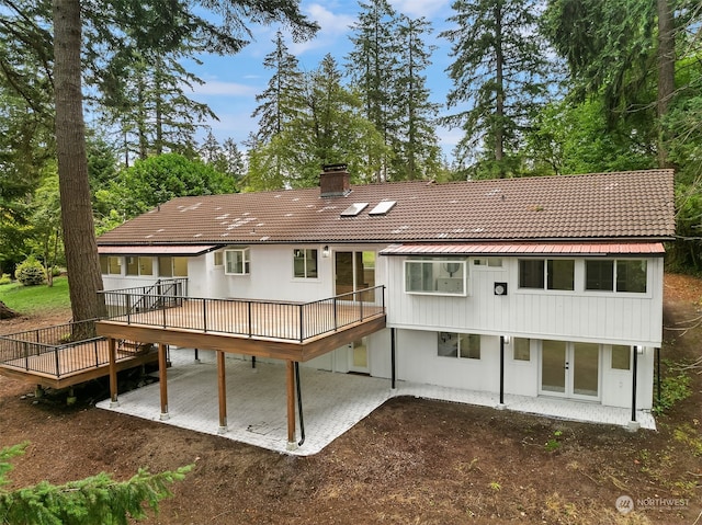 back of property featuring a wooden deck and a patio