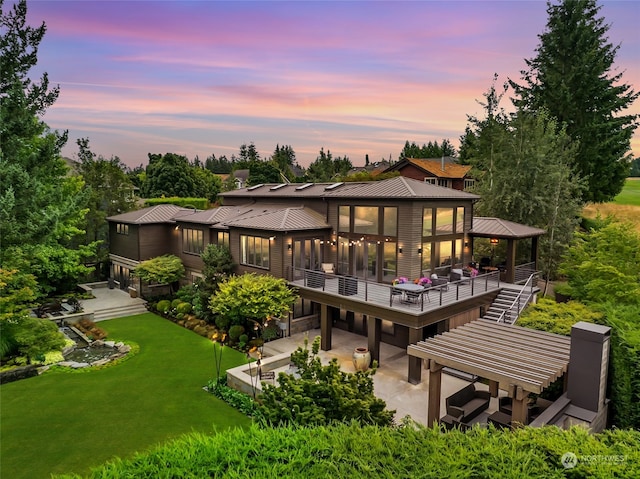 back house at dusk featuring a patio, a lawn, and a pergola