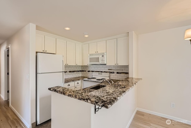 kitchen featuring tasteful backsplash, white cabinets, white appliances, and kitchen peninsula