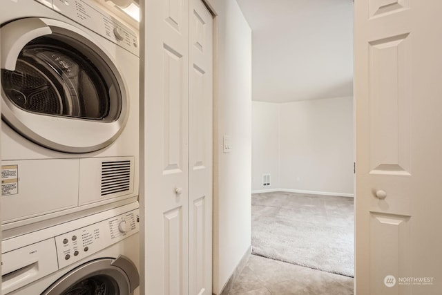 clothes washing area with light carpet and stacked washer and clothes dryer