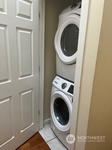 laundry area with stacked washing maching and dryer and hardwood / wood-style flooring