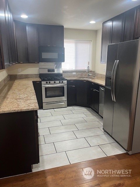 kitchen featuring sink, light tile patterned floors, light stone counters, and stainless steel appliances