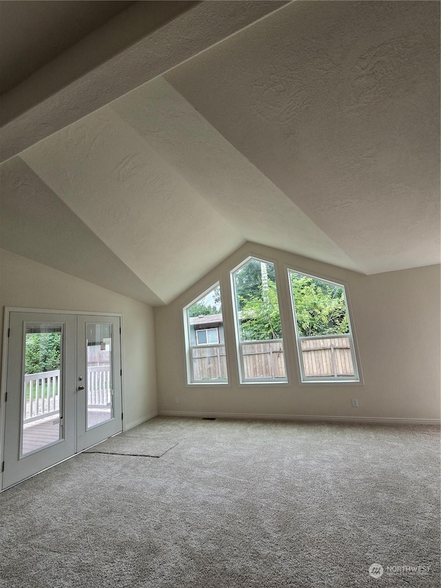 additional living space with lofted ceiling, french doors, carpet flooring, and a textured ceiling