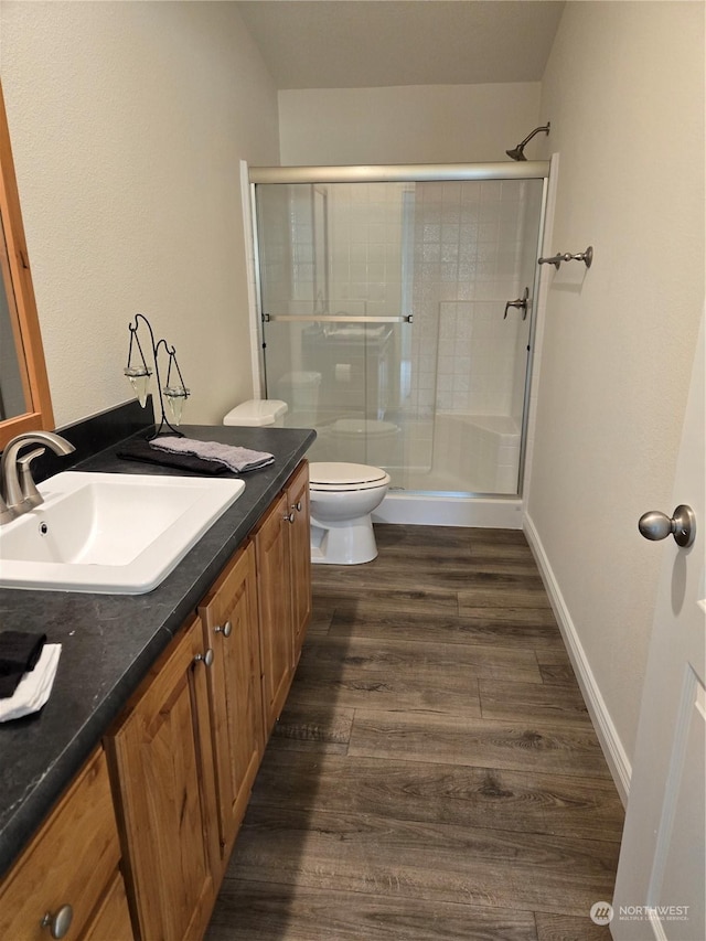 bathroom featuring vanity, wood finished floors, a shower stall, and toilet