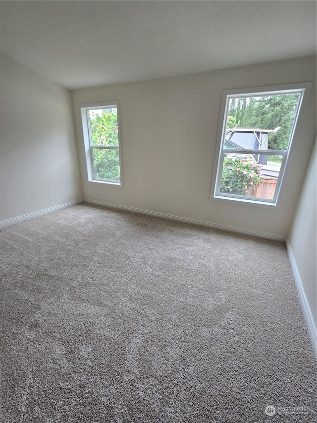 unfurnished room featuring carpet and baseboards