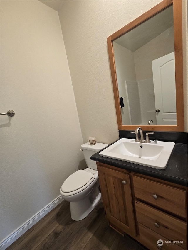 bathroom with toilet, baseboards, wood finished floors, and vanity