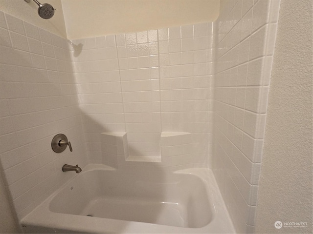 bathroom with washtub / shower combination and a textured wall