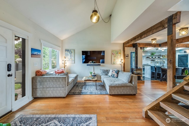 living room with high vaulted ceiling, light hardwood / wood-style flooring, and a wood stove