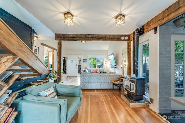 living room with hardwood / wood-style flooring, a wood stove, and beamed ceiling