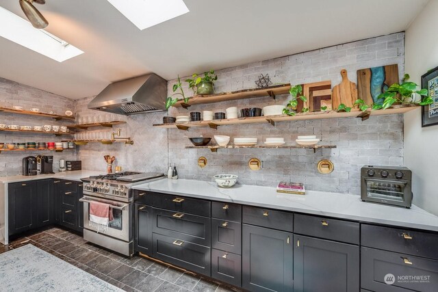 kitchen with high end stainless steel range oven, wall chimney exhaust hood, and lofted ceiling with skylight