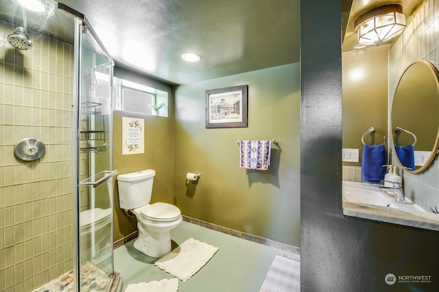 bathroom featuring vanity, a shower with shower door, and toilet